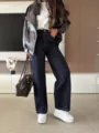 Detailed view of women's contrast stitching wide leg denim pants and brown leather jacket outfit. - S / Bottoms / Dark Blue