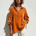 Close-up view of the orange velvet V-neck blouse showing textured fabric and drawstring detail. - S / Tops / Orange