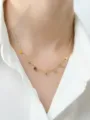 Gros plan détaillé du collier délicat doré à disques porté au cou avec une chemise blanche. - Or