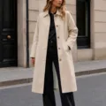 Vue de détail d'un trench-coat mi-long uni à revers et simple boutonnage pour femme. - S / Hauts / Abricot