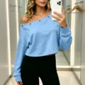 Primo piano dettaglio del crop top azzurro monospalla con occhielli metallici e maniche lunghe. - Taglia S / Top / Blu