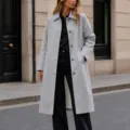 Vue détaillée d'un élégant trench-coat mi-long gris clair pour femme avec revers et boutons. - Gris clair