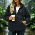 Femme veste coupe-vent noire à capuche vue de détail, manteau imperméable extérieur. - XL / Hauts / Noir