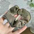 Close-up detail of retro satin hair scrunchie with elegant lace edge, daily hair accessory. - Coffee