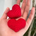 Handmade red crochet heart earrings close-up showing cute 3D knit texture and metal pin details. - Red