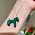 Close up of a cute green enamel horse pendant necklace worn on wrist, exquisite jewelry detail - Green Pony Pendant Necklace