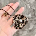 Close-up detail of the leopard print acrylic flower pendant with a central pearl accent. - Brown Leopard