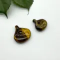 Natural tiger eye stone magatama pendant closeup, polished surface with chatoyant effect. - Tiger's Eye