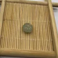 Detail shot of a carved gemstone pumpkin bead on a wooden tray, ideal for DIY jewelry making. - Green Aventurine