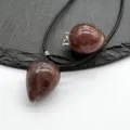 Primo piano dettaglio ciondolo in cristallo gemma a goccia con collana di corda nera. - Quarzo rosa