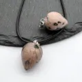 Detailed close-up of natural stone teardrop crystal pendant showing unique texture and patterns. - Rhodonite