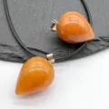Close-up detail of orange gemstone teardrop pendants with black cord on slate background. - Yellow Aventurine