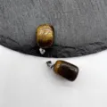 Close-up detail of natural tiger eye stone square pendant with metallic clasp on slate. - Tiger Eye (1 Piece)