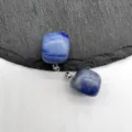Detailed close-up of blue crystal square stone pendant with silver bail on textured surface. - Blue Aventurine