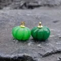 Primo piano del ciondolo a zucca in giada verde scolpita con anello dorato per bigiotteria. - calcedonio verde