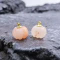 Close-up detail shot of cute carved crystal pumpkin pendants with gold loops for DIY jewelry. - Golden Silk Jade