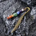 Close-up detail of vintage bronze feather metal bookmark with colorful chakra crystal bead accents. - Irregular Bead Style