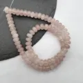 Dettaglio in primo piano di perline abaco in quarzo rosa naturale, lucide, perfette per gioielli. - Quarzo rosa