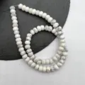 Primo piano di perline abaco in pietra bianca naturale con finitura lucida per fai da te. - Howlite