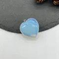 Primo piano dettagliato di un ciondolo in opale a forma di cuore su pietra scura. - Opale