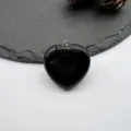 Black heart-shaped natural stone pendant detail, smooth polished gemstone jewelry accessory. - Obsidian