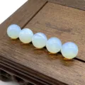 Close-up detail of smooth semi-precious stone round beads arranged neatly on wood tray. - Opalite (Synthetic)