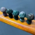 Detail view of natural crystal carved stone mushrooms displayed neatly on a wooden stand for decor. - Indian Agate (1 Piece)