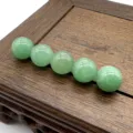 Detailed close-up view of 10mm non-hole green gemstone round beads displayed on wooden base. - Green Aventurine