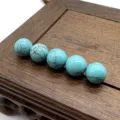 Close-up detail of smooth turquoise spotted stone round beads, undrilled DIY jewelry material. - Turquoise (Synthetic)
