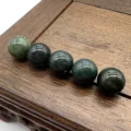 Close-up of natural green speckled gemstone loose beads, smooth round shape detail view. - Indian Agate