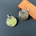 Detailaufnahme eines runden Edelstein-Anhängers mit einzigartiger grün-roter Textur und Öse. - Drachenblutstein