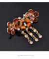 Close-up of elegant butterfly hair claw clip with sparkling rhinestones and hanging crystal tassels. - Champagne