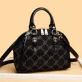 Elegante borsa a mano a cupola nera con finiture in pelle verniciata e accessori dorati. - Nero