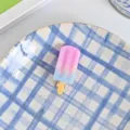 Gros plan en gros plan d'une charmante pince à cheveux glacée en dégradé sur une assiette. - Pince à Cheveux Glace Rouge Rose