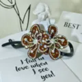 Close-up detail of luxury rhinestone hair claw clip, sparkling brown crystal butterfly design. - Style 6