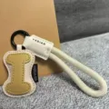Close-up detail of the leather letter keychain and braided wrist strap with metal hook. - Letter I