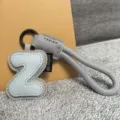 Closeup of letter Z leather keychain bag charm with grey braided strap and black metal ring. - Letter Z