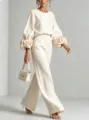 Primo piano dell'elegante set crema con polsini floreali 3D drammatici e pantaloni larghi alla moda. - XS / Top e Pantaloni / Bianco latte