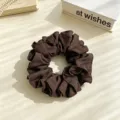 Vue de détail d'un chouchou en tissu marron foncé, design plissé élégant pour coiffure quotidienne. - Brun