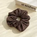 Vue détaillée d'un chouchou en soie métallique marron, élastique brillant pour queues de cheval. - Marron