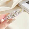 Gros plan détaillé d'une pince à cheveux rose douce en strass et perles, étiquette métal. - Pince Ovale Rose