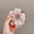 Gros plan détaillé de chouchou pour cheveux en organza brillant, design souple et duveteux. - Kaki