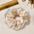 Gros plan détaillé d'un élégant chouchou en satin beige et dentelle, accessoire chic. - Light jaune