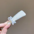 Close-up detail shot of the sparkling crystal hairpin featuring an elegant pearl bow design. - Bow Triangle / Light Yellow