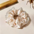 Gros plan detaille d un chouchou elegant en satin champagne et tulle, accessoire de mode chic - Blanc Cassé