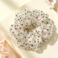 Gros plan détaillé d'un chouchou en résille blanche à pois noirs, tissu doux et design élégant. - S / Pois Blancs