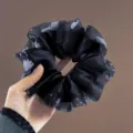 Vue de détail rapprochée du chouchou en satin noir élégant orné de perles et de dentelle fine. - Chouchou Satin Noir