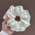 Gros plan détaillé du chouchou en satin blanc avec une élégante bordure en dentelle perlée. - Chouchou en Satin Blanc