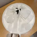 Gros plan de la pince à cheveux nœud en mousseline blanche avec de longs rubans sur assiette. - Blanc