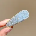 Gros plan de barrette à cheveux strass scintillants, détail cristal bleu, accessoire brillant. - Pince à Cheveux Strass Triangle Bleu
